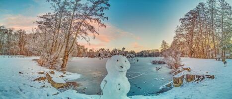 imagen terminado un congelado lago en el Mañana ligero con un monigote de nieve foto