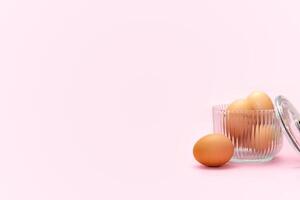 Eggs in ribbed glass on pink background photo