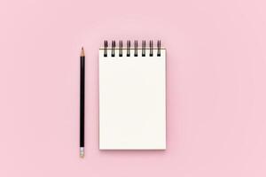 Blank notebook and pencil on pink background photo