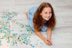 girl collects a puzzle from small pieces photo