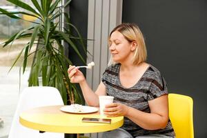 woman in a cafe drinks coffee in a paper cup and eats cake photo