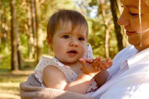 cute baby girl in her mother's arms in the park photo