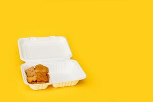 abierto almuerzo caja con para niños galletas en un amarillo antecedentes con Copiar espacio foto