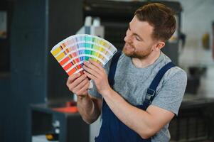 Man working in printing house with paper and paints photo