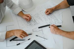 dos colegas que se discute datos trabajando en arquitectónico proyecto a construcción sitio a escritorio en oficina foto