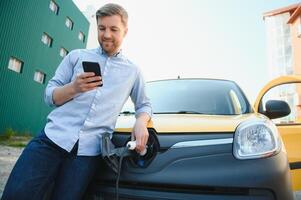 Smiling man unplugging the charger from the car photo