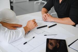 dos personas sentar en frente de construcción plan y hablar acerca de el arquitectura foto