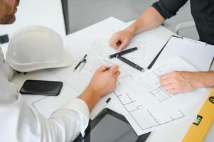 ingeniero o arquitecto trabajo en equipo trabajando en construcción proyecto con edificio modelo y Plano en oficina. construcción concepto. foto