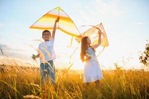 niños lanzamiento un cometa en el campo a puesta de sol foto