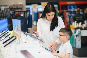 Beautiful young woman choosing which smart phone to buy. Shopping in tech store. photo