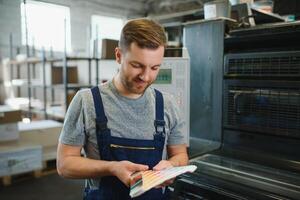 Man working in printing house with paper and paints photo