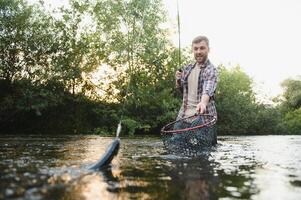 Fisherman catches a trout on the river in summer photo