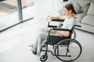 Young woman in wheelchair at home in living room. photo