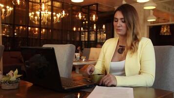 Beautiful business woman with long blond hair examining working papers and drinking tea while sitting at the table. Business style. video