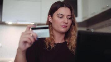 mooi vrouw met lang donker haar- online bank met een computer muis Aan de internet met een credit kaart Bij huis Bij de tafel hebben een mooi zo humeur en lachend. hd video