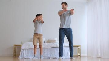 Family fitness at home, Father coach, Sports kid, Fun gymnastics. Sportive dad and son doing physical exercise squatting together while standing on the floor at home video