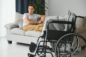 Brunette woman on couch near wheelchair photo