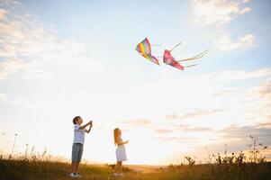 niños lanzamiento un cometa en el campo a puesta de sol foto