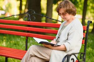 Retired woman reading a book on the bench photo