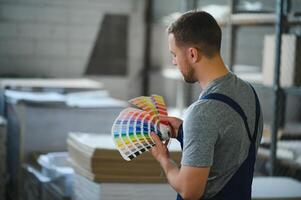 hombre trabajando en impresión casa con papel y pinturas foto