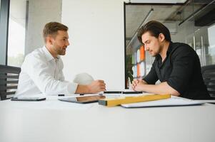 Two colleagues discussing data working on architectural project at construction site at desk in office photo