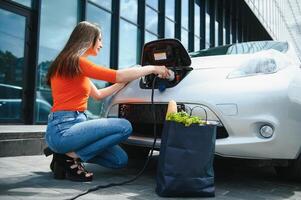 Woman charging electro car at the electric gas station photo