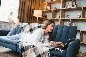 Young woman lying on couch with laptop. photo