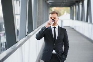 Takeaway coffee. Walk and enjoy fresh hot coffee. Waiting for someone in street. Man bearded hipster drink coffee paper cup. Businessman well groomed enjoy coffee break outdoors urban background photo