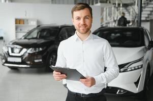 retrato de mente abierta profesional vendedor en carros sala de exposición, caucásico hombre en blanco formal camisa soportes siguiente a lujoso coche y mira a cámara foto