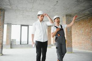 Engineer and worker checking project at building site background, construction site at sunset in evening time photo