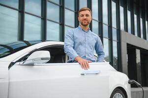 hombre cargos un eléctrico coche a el cargando estación foto