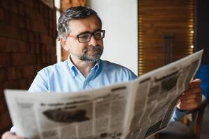 activo mayor hombre leyendo periódico y Bebiendo café en restaurante foto