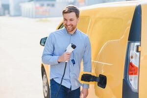 Smiling man unplugging the charger from the car photo