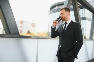 Takeaway coffee. Walk and enjoy fresh hot coffee. Waiting for someone in street. Man bearded hipster drink coffee paper cup. Businessman well groomed enjoy coffee break outdoors urban background photo