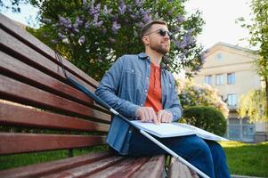 Visually impaired man with walking stick, sitting on bench in city park. Copy space photo