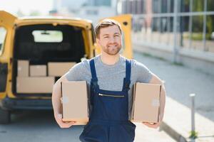 delivery service employee. Portrait of man working in delivery service. Portrait of courier with box. Courier next to minivan. Delivery service career. photo