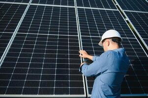 Worker technician connecting heavy solar photo voltaic panels to high steel platform. Exterior solar system installation, alternative renewable green energy generation concept