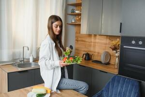 hermosa joven mujer es preparando vegetal ensalada en el cocina. sano alimento. vegano ensalada. dieta. dieta concepto. sano estilo de vida. Cocinando a hogar. foto