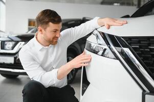 Man adult customer male buyer client chooses auto wants to buy new automobile touch check car in showroom vehicle salon dealership store motor show indoor. Sales concept photo