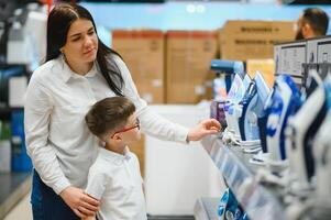 Woman with son choosing electric iron in electronics store photo