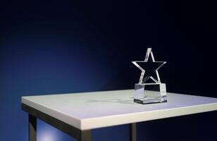 Star-shaped award made of glass on a white table with a spotlight on it and copy space photo