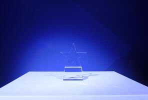 Star-shaped award made of glass on a white table with a spotlight on it and copy space photo