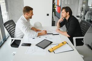 dos Ingenieria trabajando juntos y utilizando digital tableta mirando Plano y análisis con arquitectónico plan en escritorio foto