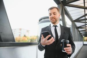 cerca arriba grave empresario Bebiendo tomar lejos café a calle. retrato de negocio hombre esperando con café a Vamos exterior. oficina empleado mirando lejos a calle. masculino profesional tomar descanso foto