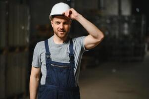 Portrait of happy male worker in warehouse standing between shelves. photo
