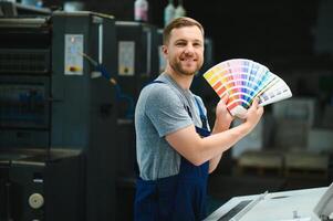 Man working in printing house with paper and paints photo