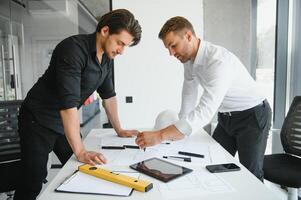 dos personas sentar en frente de construcción plan y hablar acerca de el arquitectura foto