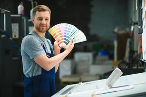 Man working in printing house with paper and paints photo