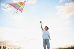 Little boy on summer vacation having fun and happy time flying kite on the field. photo
