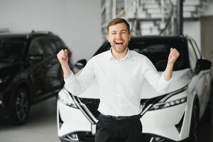 Young handsome man at show room standing near car photo